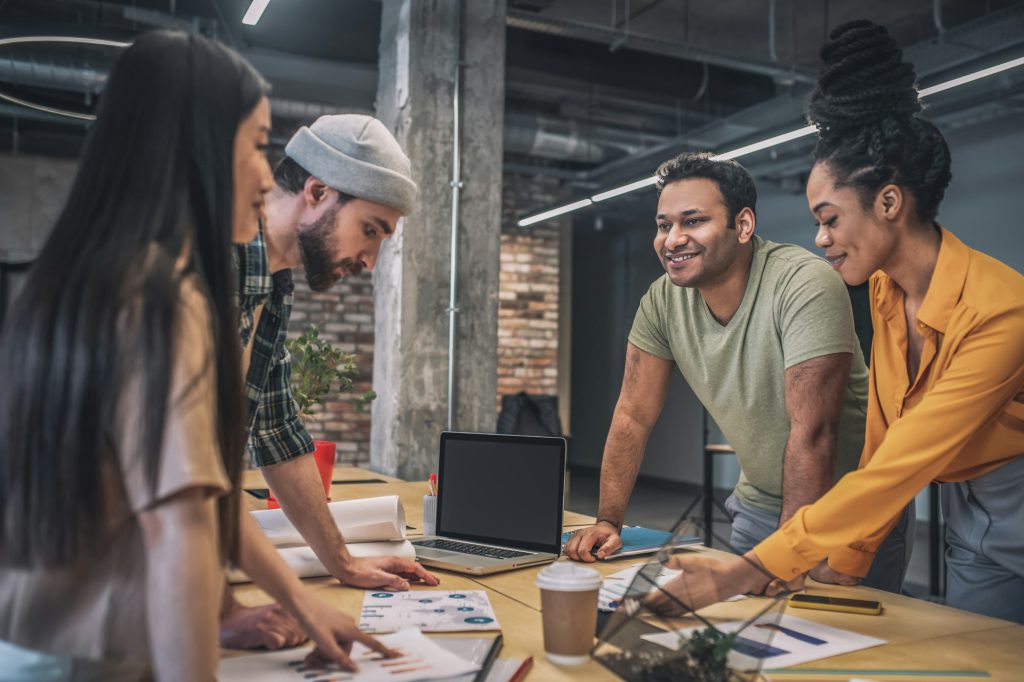 Four interracial smiling people in office